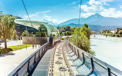 Hungerburg Funicular station with tracks, river, and mountain view in Innsbruck, Austria.