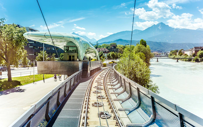 Hungerburg Funicular station with tracks, river, and mountain view in Innsbruck, Austria.