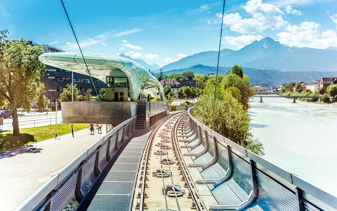 Hungerburg Funicular station with tracks, river, and mountain view in Innsbruck, Austria.