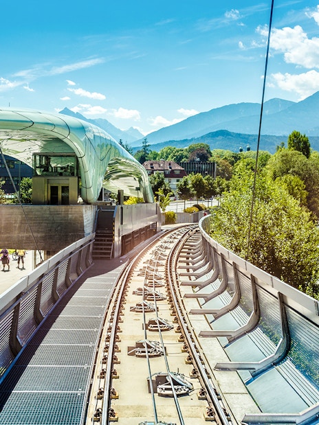 Hungerburg Funicular station with tracks, river, and mountain view in Innsbruck, Austria.
