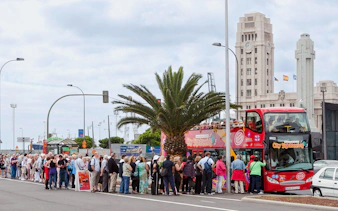 Tourists boarding Santa Cruz hop-on hop-off bus near city landmarks.
