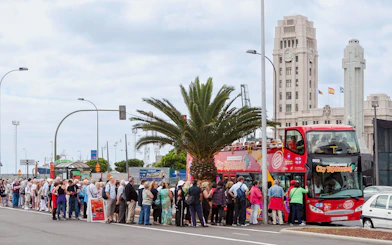 Tourists boarding Santa Cruz hop-on hop-off bus near city landmarks.