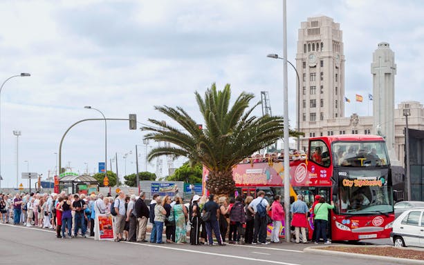 Tourists boarding Santa Cruz hop-on hop-off bus near city landmarks.