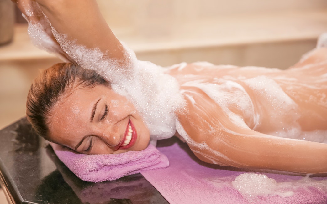 Woman enjoying foam massage in a hammam spa.