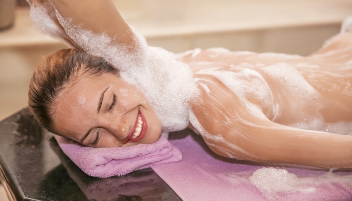 Woman enjoying foam massage in a hammam spa.