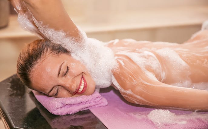 Woman enjoying foam massage in a hammam spa.