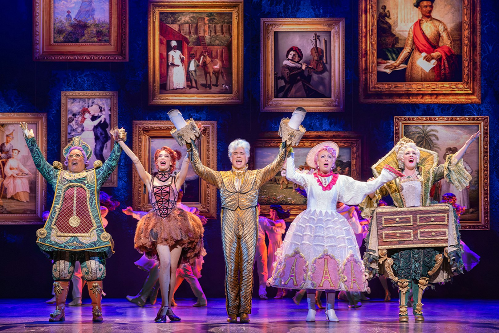 Performers in colorful costumes on stage during a Beauty and the Beast musical scene.