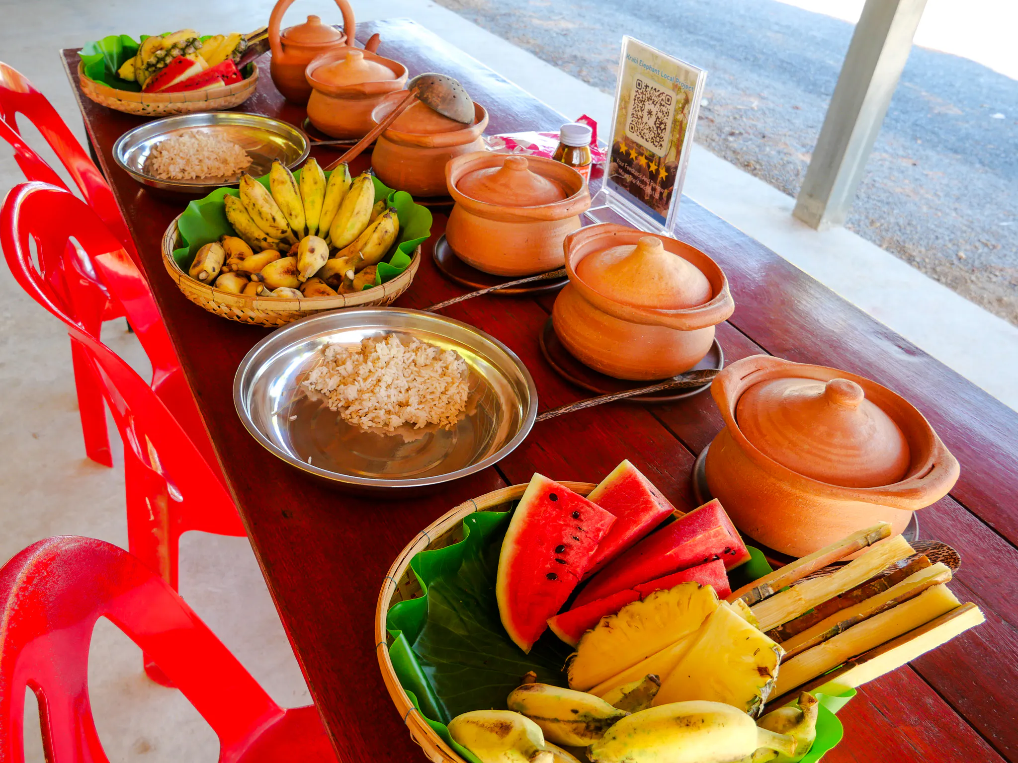 Traditional Thai meal setup with fruits and clay pots at Krabi Elephant Local Project workshop.