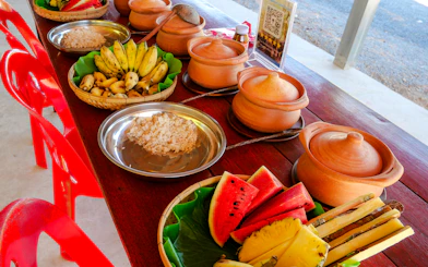 Traditional Thai meal setup with fruits and clay pots at Krabi Elephant Local Project workshop.