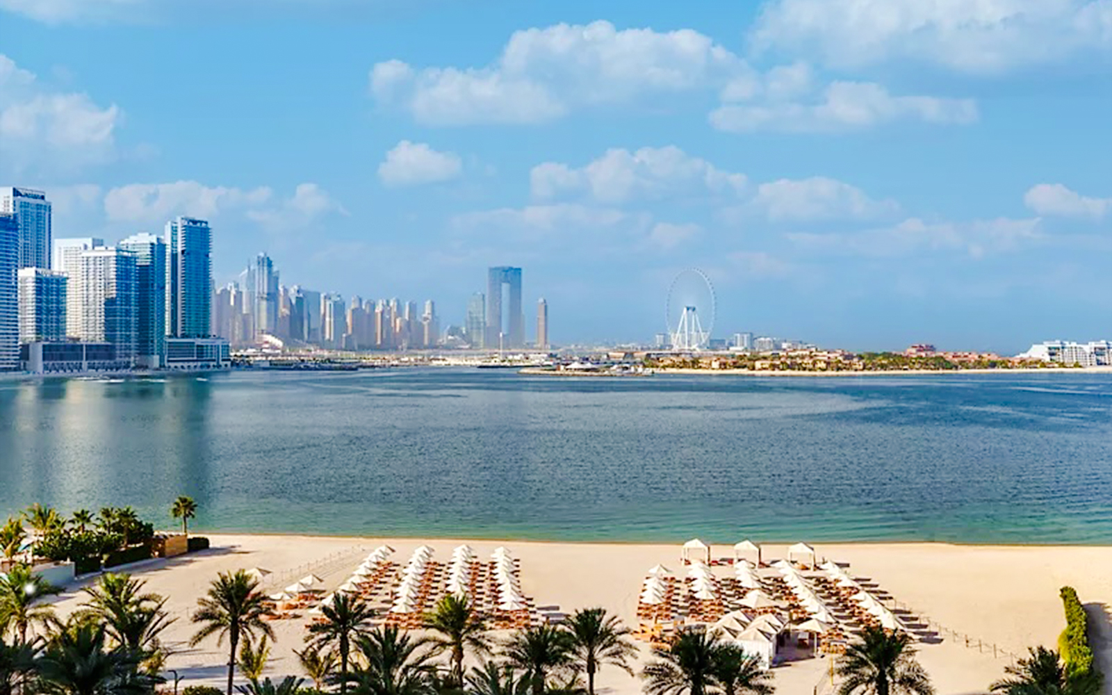 Beachfront view from Fairmont Hotel overlooking Dubai skyline and Ferris wheel.