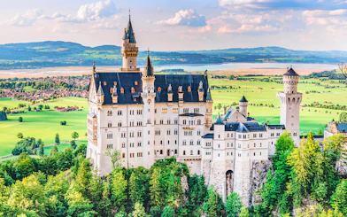 Neuschwanstein Castle in Bavaria, Germany, surrounded by lush green landscape.
