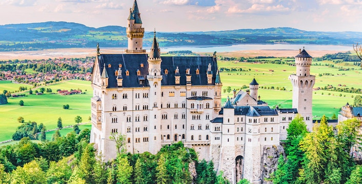 Neuschwanstein Castle in Bavaria, Germany, surrounded by lush green landscape.