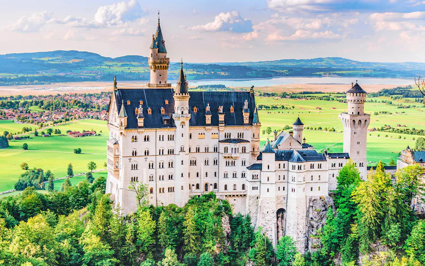 Neuschwanstein Castle in Bavaria, Germany, surrounded by lush green landscape.