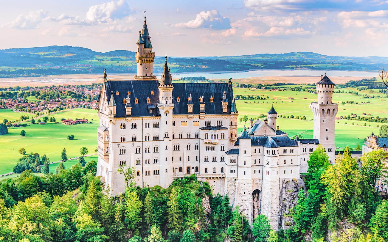 Neuschwanstein Castle in Bavaria, Germany, surrounded by lush green landscape.