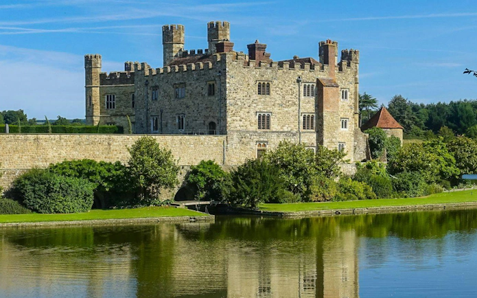 Leeds Castle in Kent, England, surrounded by a moat and lush greenery.