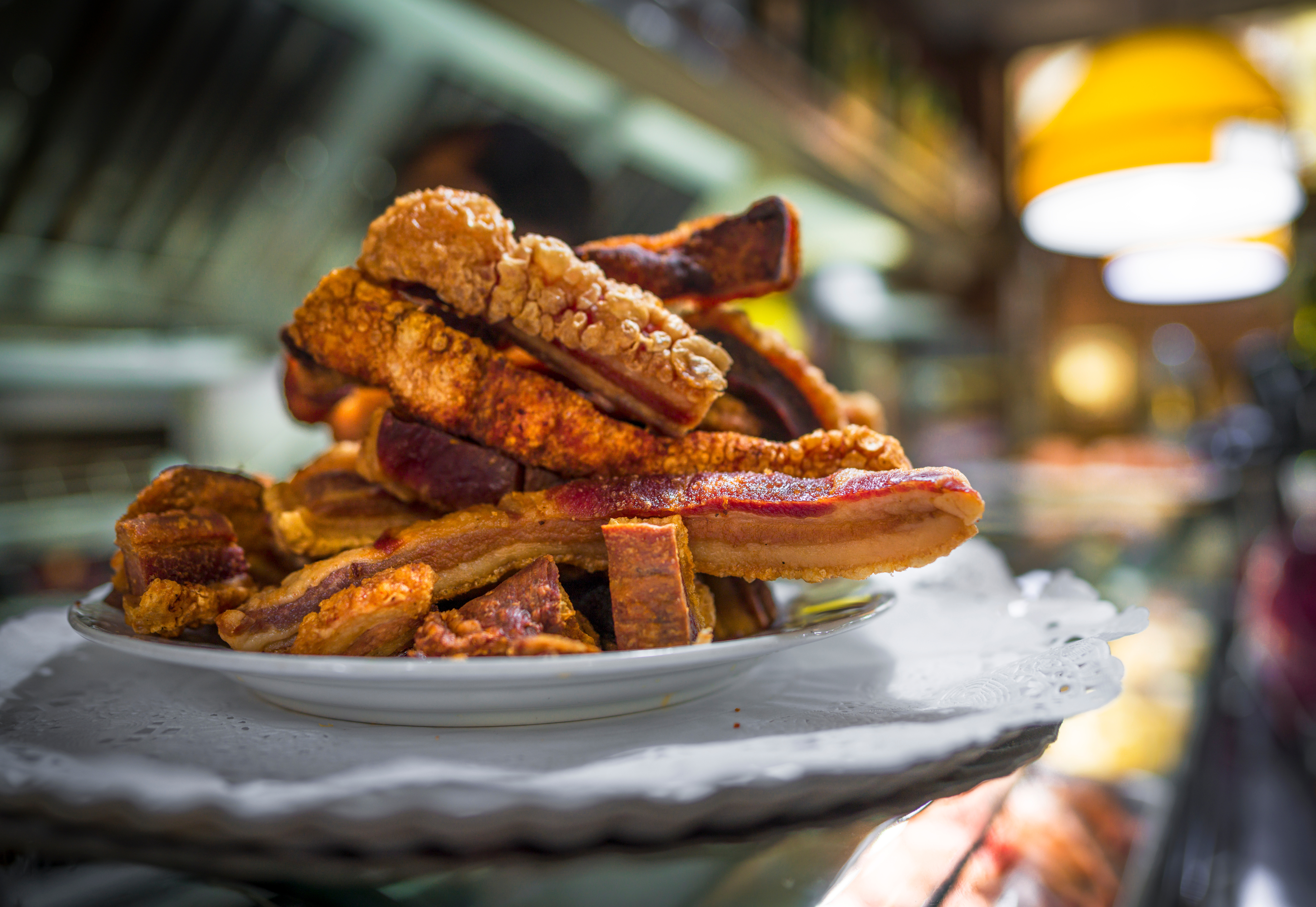 Torreznos pork belly on a white plate in a restaurant setting.