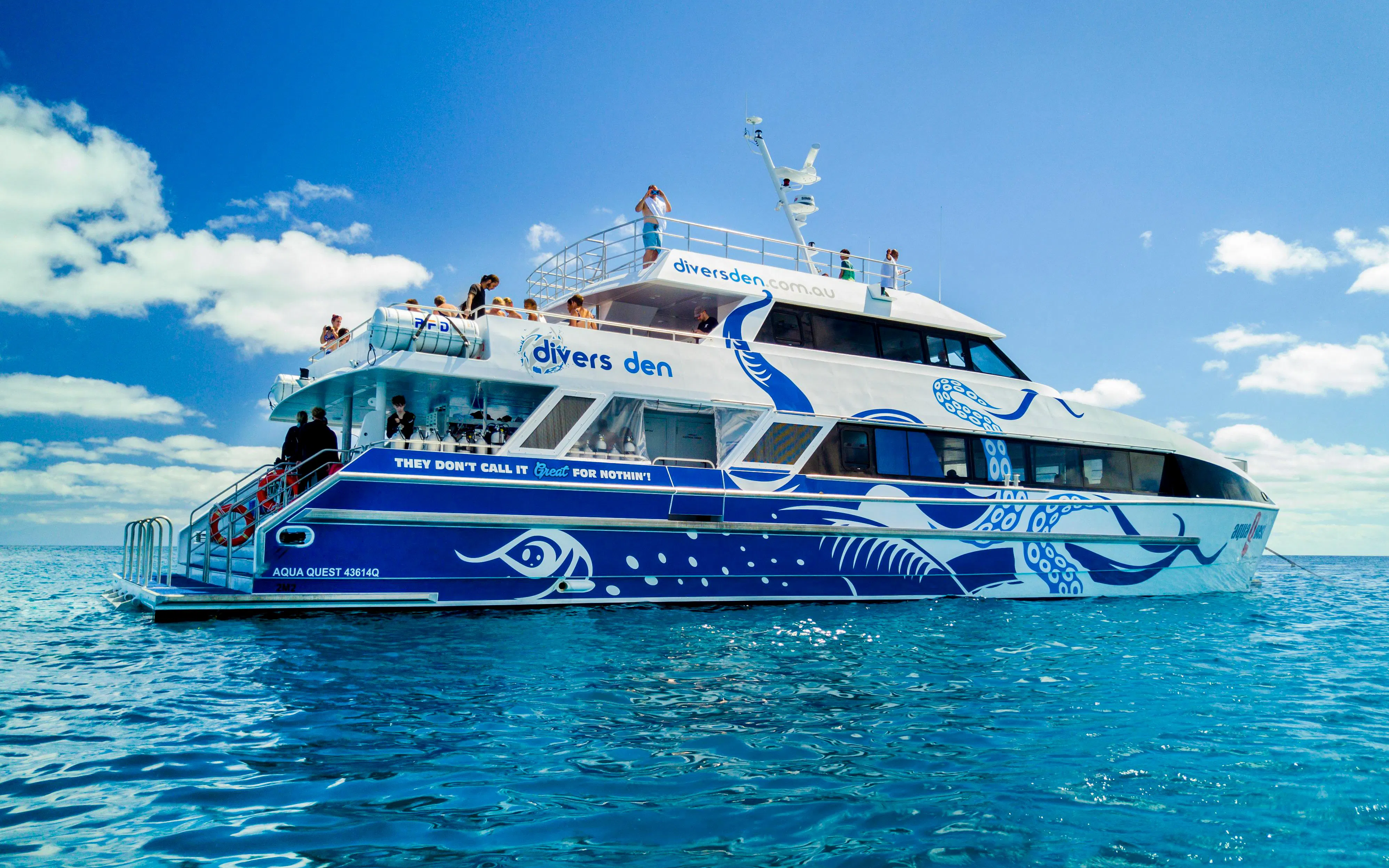 Divers Den aquavessel on clear ocean waters with passengers on deck.