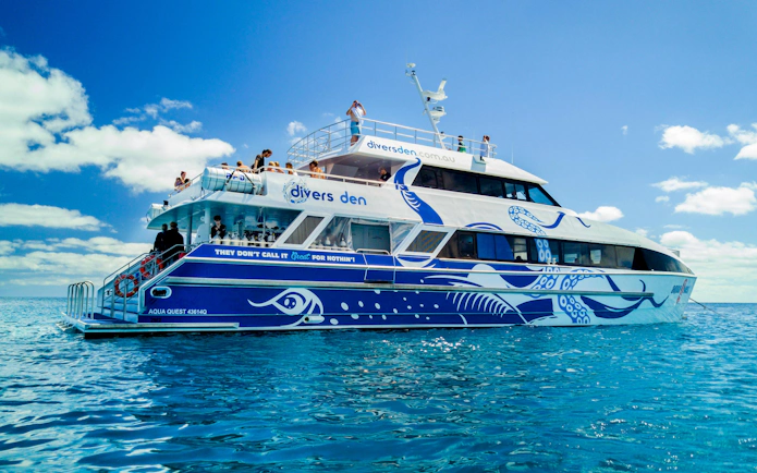 Divers Den aquavessel on clear ocean waters with passengers on deck.
