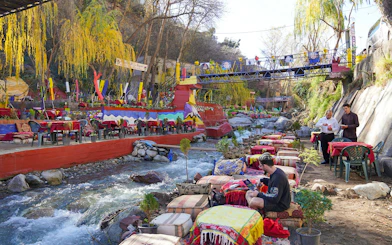 Tourist dining by a river in a colorful restaurant, Ourika Valley, Morocco.