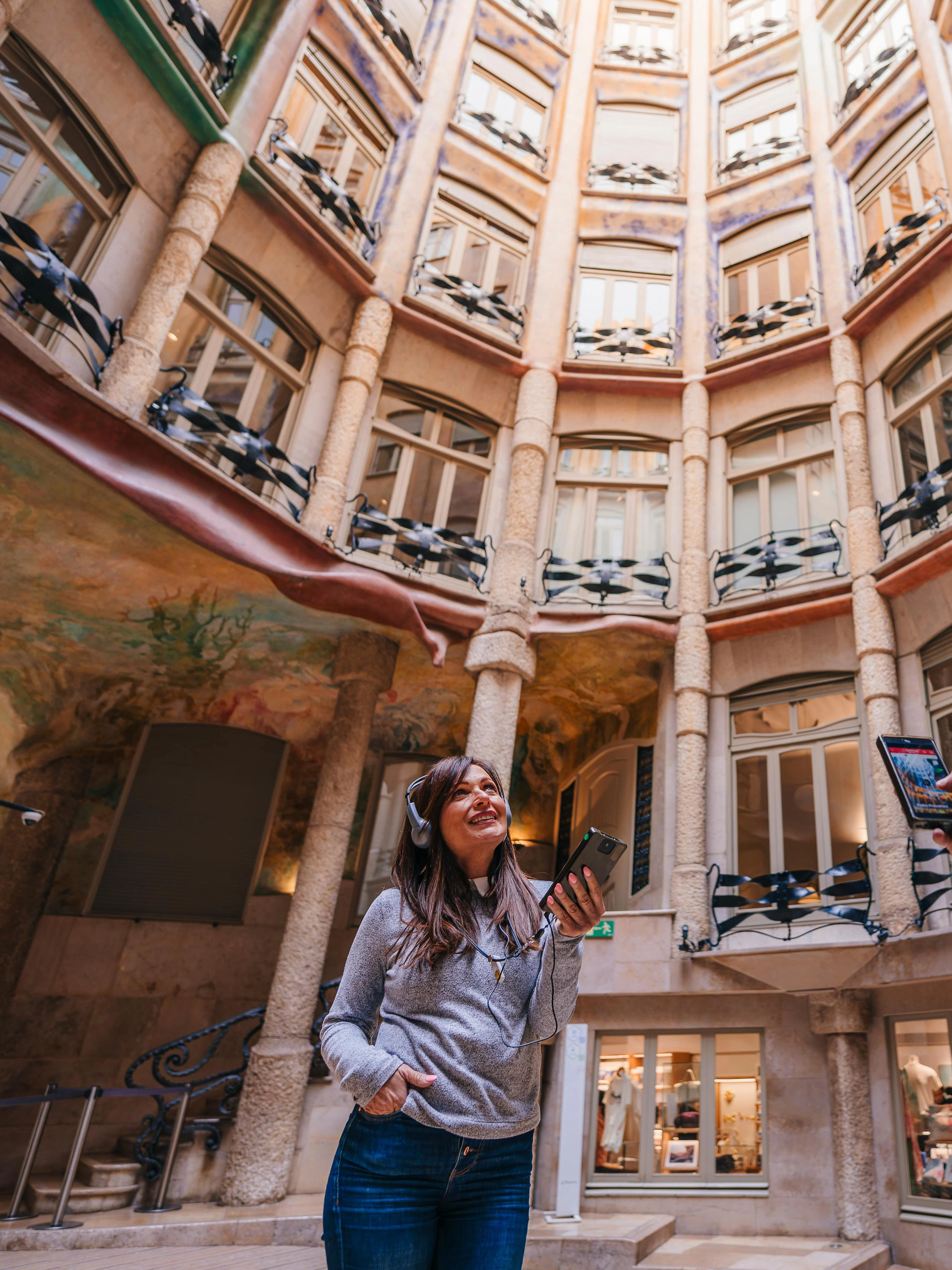 Visitors with audio guides inside La Pedrera's courtyard during a sunset tour in Barcelona.