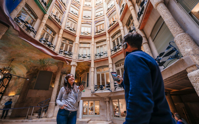 Visitors with audio guides inside La Pedrera's courtyard during a sunset tour in Barcelona.