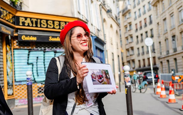 Guide showing photos during Emily in Paris Locations Walking Tour in Paris street.