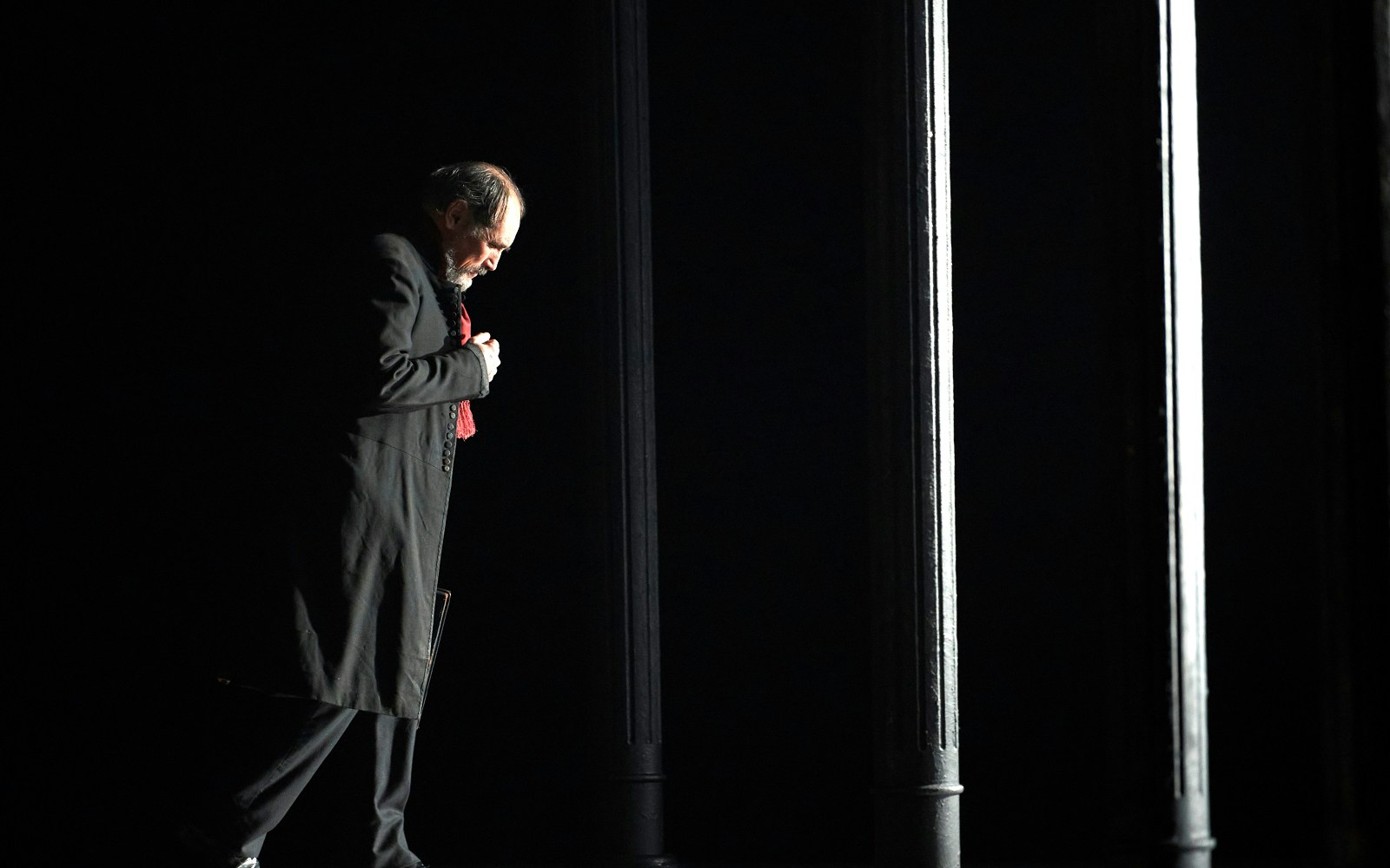 Man in dark coat standing under dim light, related to Dr Semmelweis.