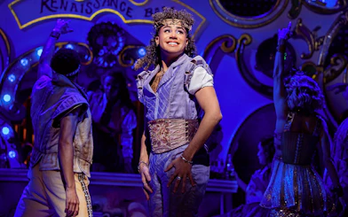 Performer on stage during & Juliet musical with vibrant Renaissance backdrop.
