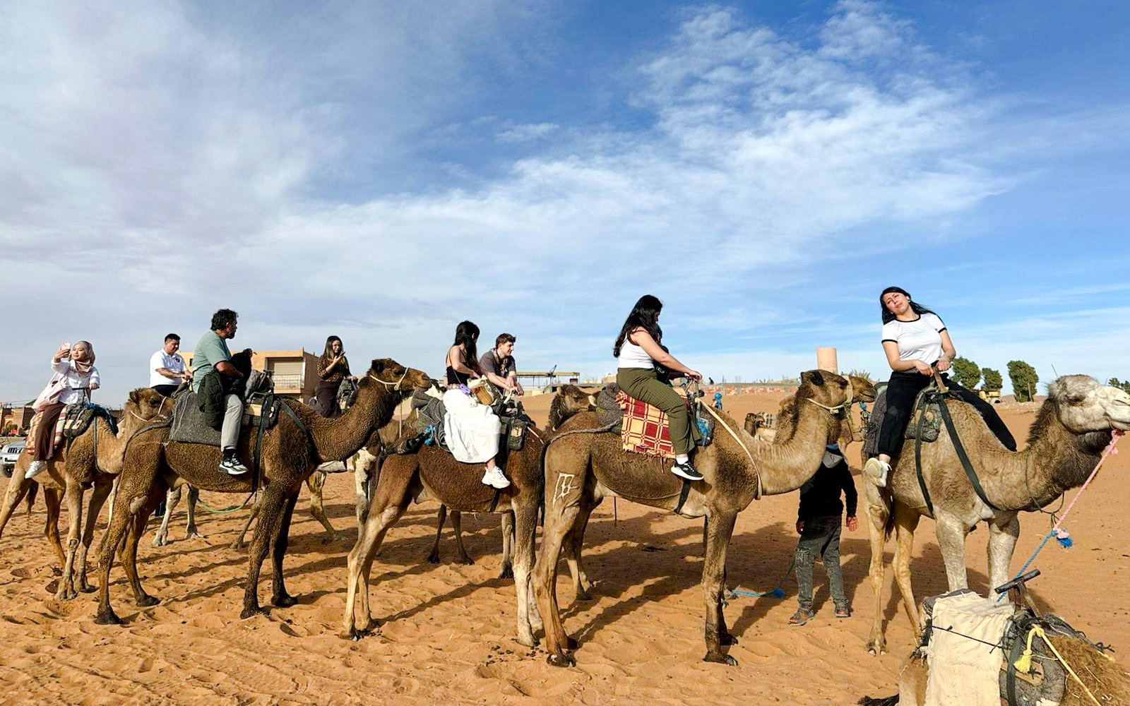 Group on camels during Merzouga desert tour with clear sky backdrop.