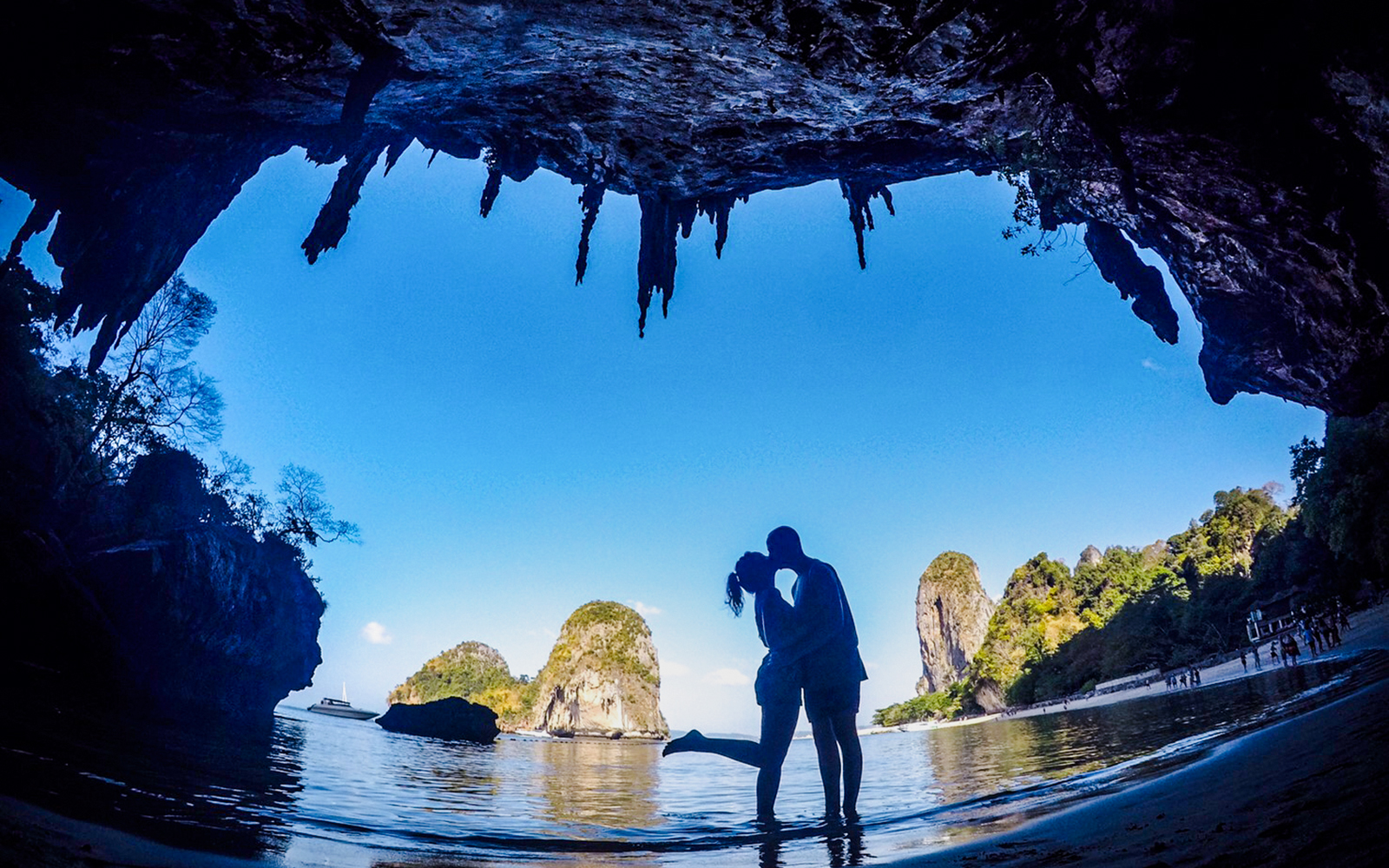 Couple kissing on a beach during Krabi 4 Islands Day Tour with limestone cliffs in the background.