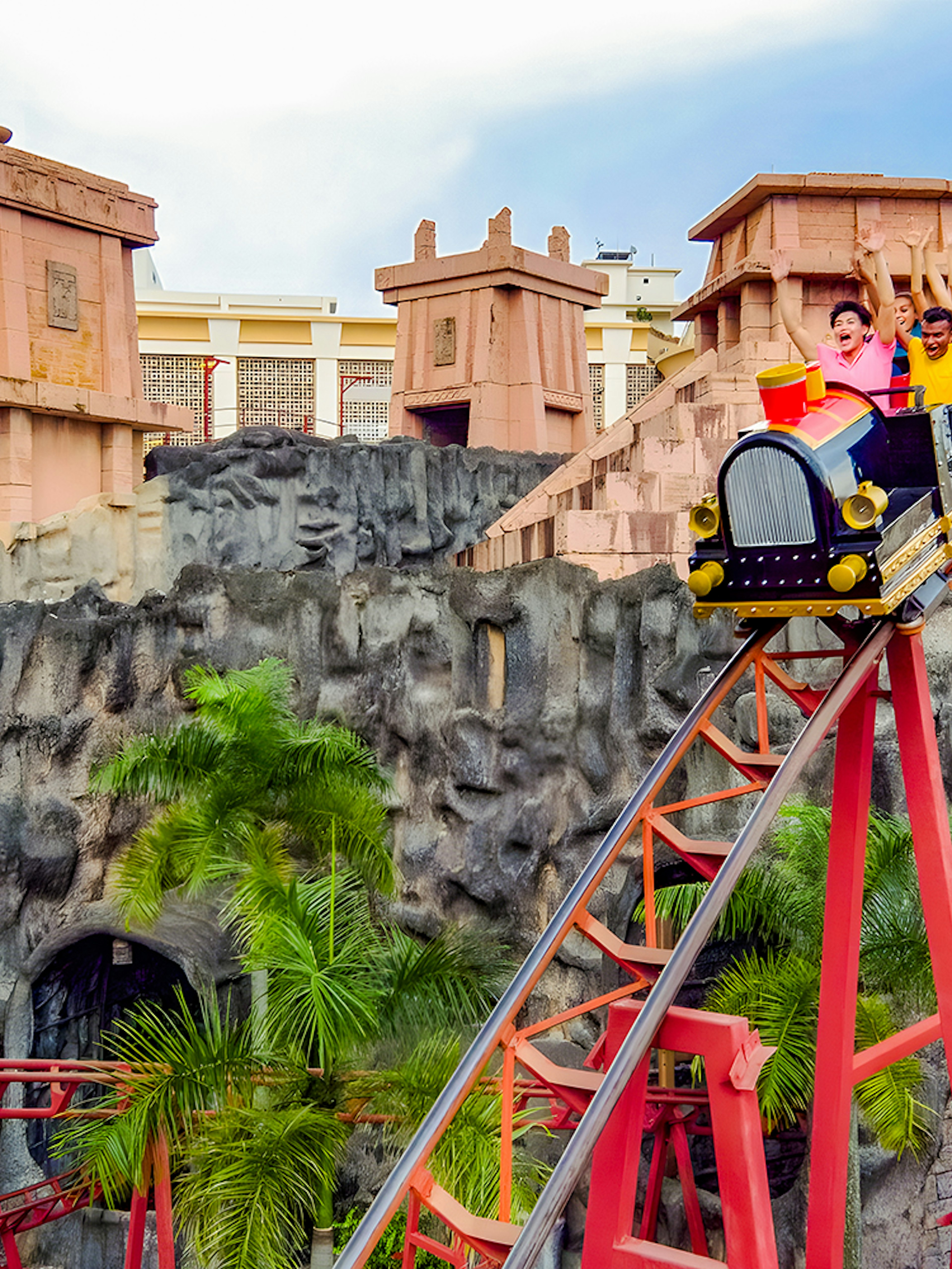 Roller coaster with riders at Sunway Lagoon amusement park.