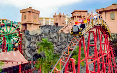 Roller coaster with riders at Sunway Lagoon amusement park.