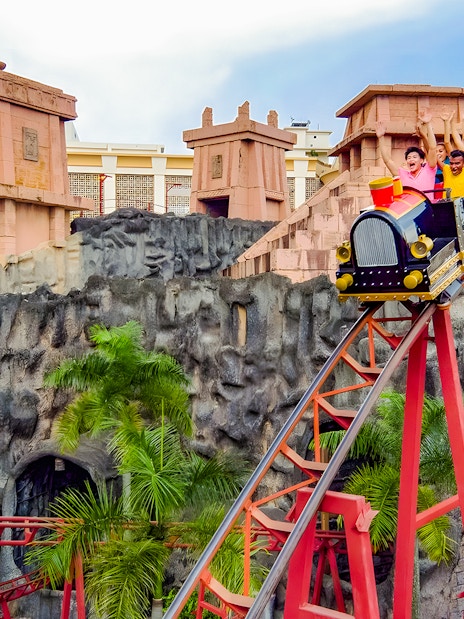 Roller coaster with riders at Sunway Lagoon amusement park.