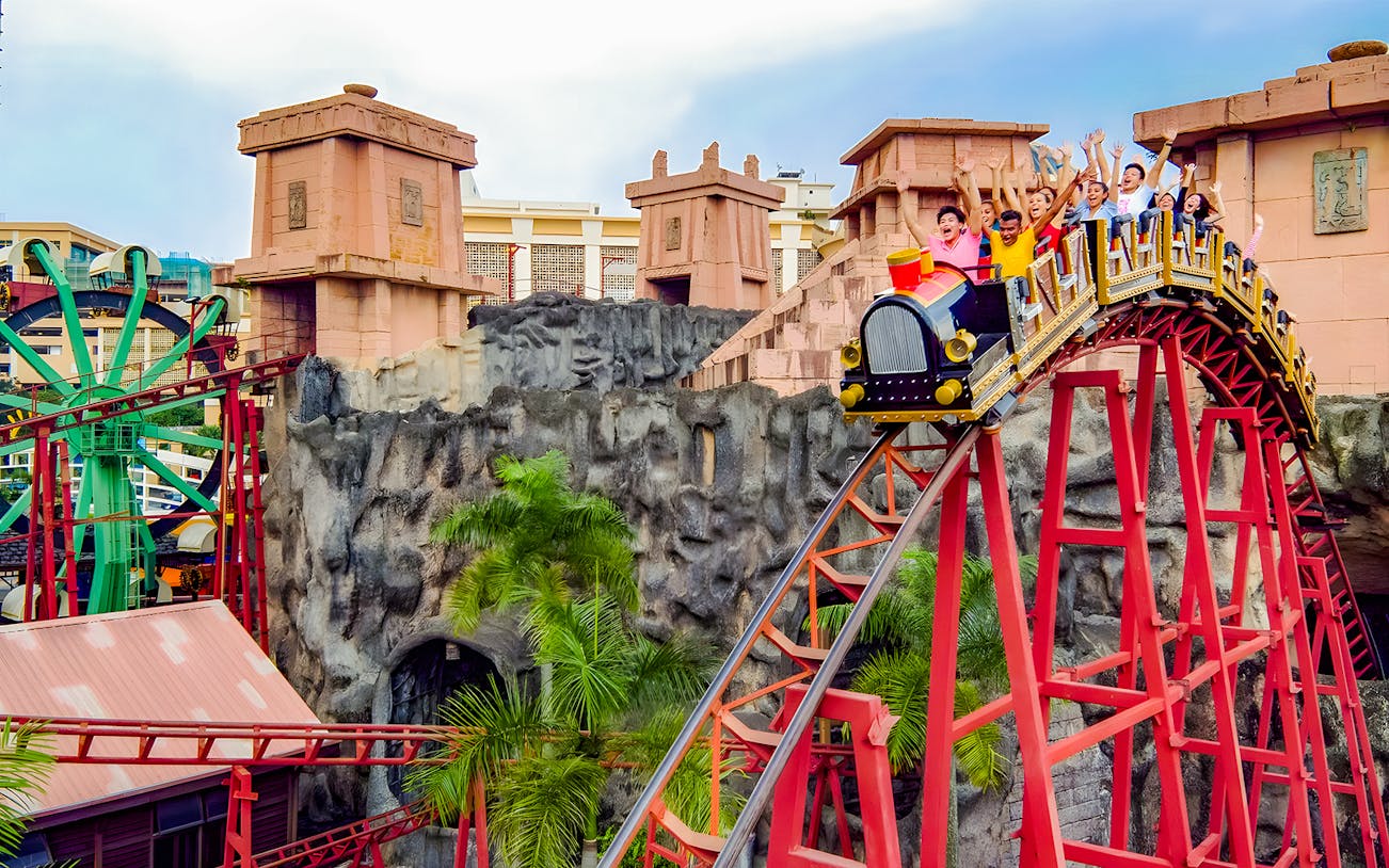 Roller coaster with riders at Sunway Lagoon amusement park.