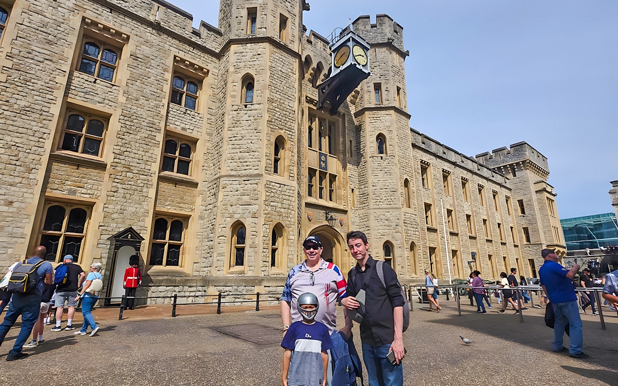 Visitors outside the historic Tower of London with a Yeoman Warder in the background.