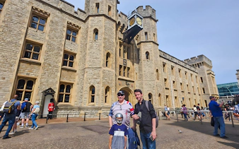 Visitors outside the historic Tower of London with a Yeoman Warder in the background.