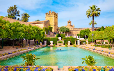 Gardens of the Alcázar of the Christian Kings in Cordoba with pool and historic architecture.