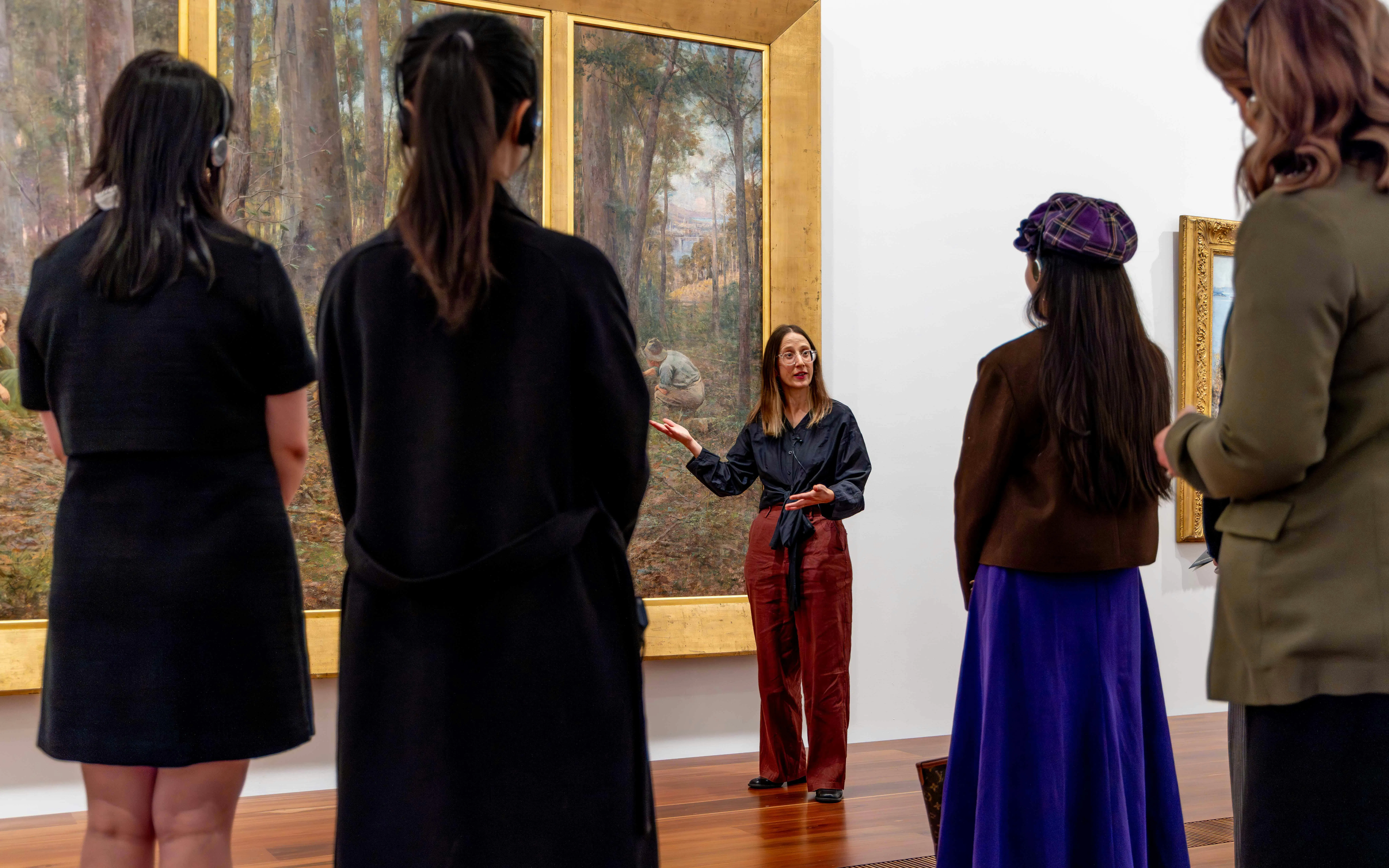 Tour guide explaining artwork to visitors at National Gallery of Victoria.