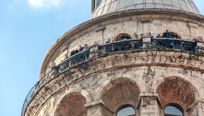 Galata Tower in Istanbul with tourists exploring the surrounding historic district.