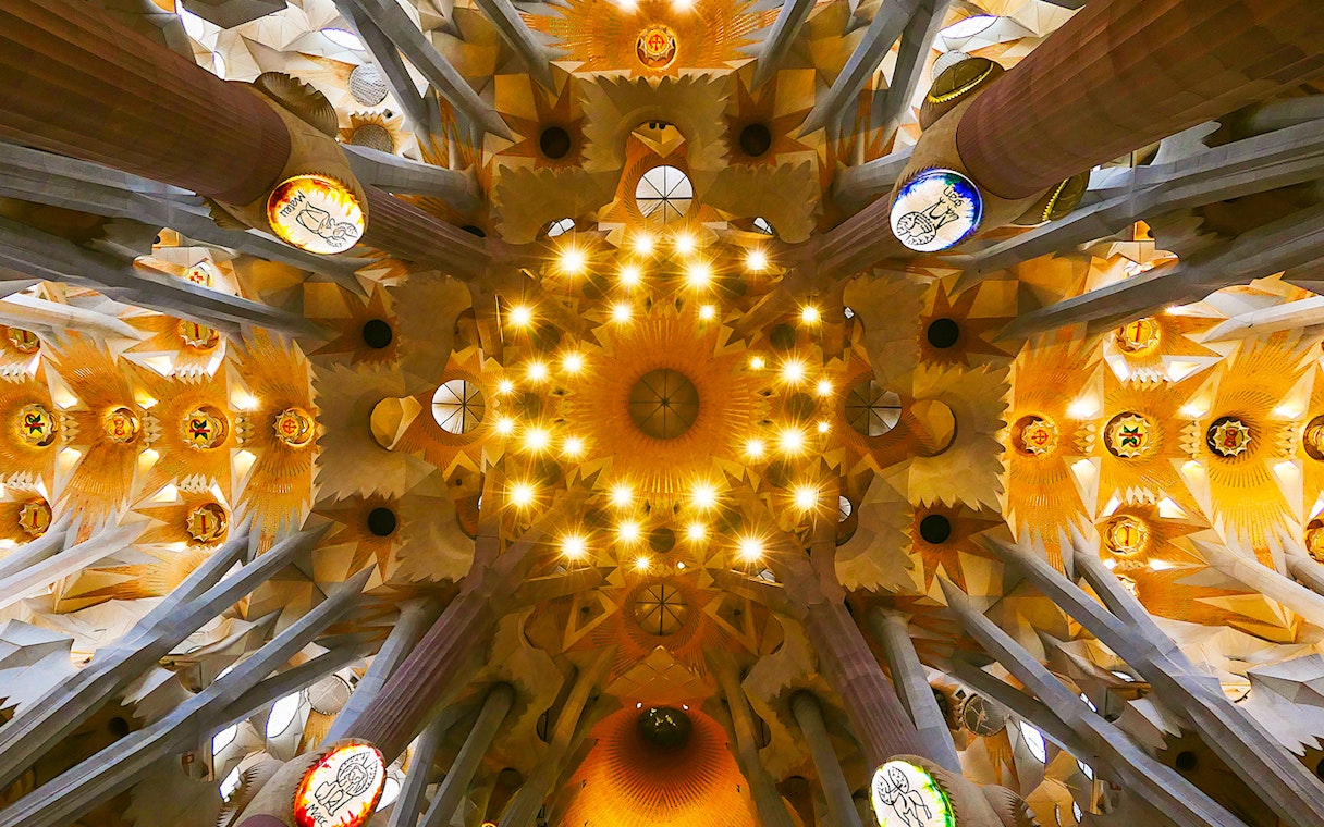 Sagrada Familia ceiling view with intricate design and lighting, Barcelona.