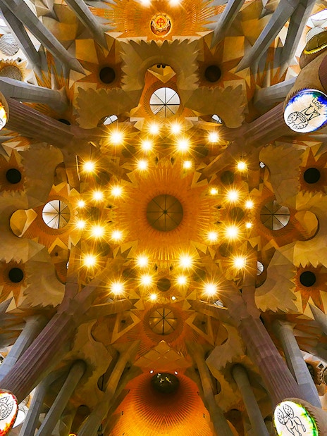 Sagrada Familia ceiling view with intricate design and lighting, Barcelona.
