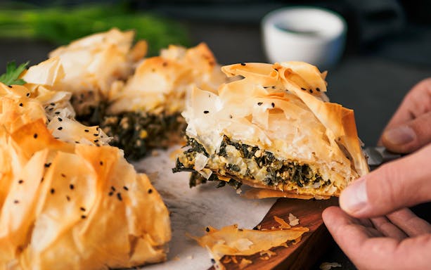Vegan spanakopita slice being served on Athens food tour.
