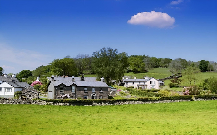 Cottages in the Lake District countryside, England, with green fields and trees.
