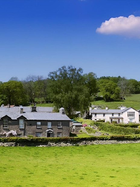 Cottages in the Lake District countryside, England, with green fields and trees.