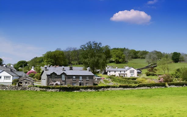 Cottages in the Lake District countryside, England, with green fields and trees.