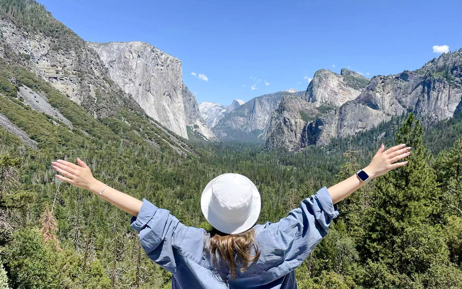 Visitor enjoying the view of Yosemite Valley, California with arms outstretched.