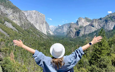 Visitor enjoying the view of Yosemite Valley, California with arms outstretched.
