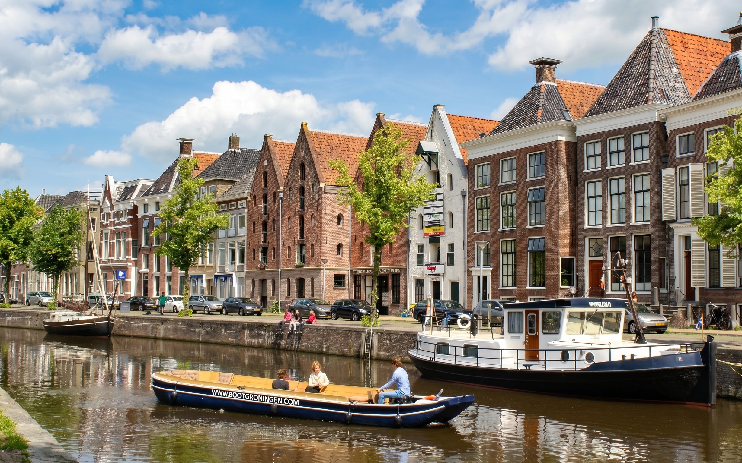 Groningen canal cruise boat passing historic buildings along the canal.