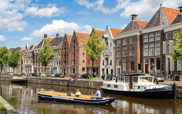 Groningen canal cruise boat passing historic buildings along the canal.