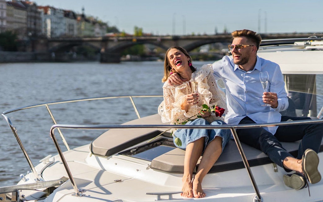 Couple enjoying Prague Beer Boat Tour with drinks on Vltava River.